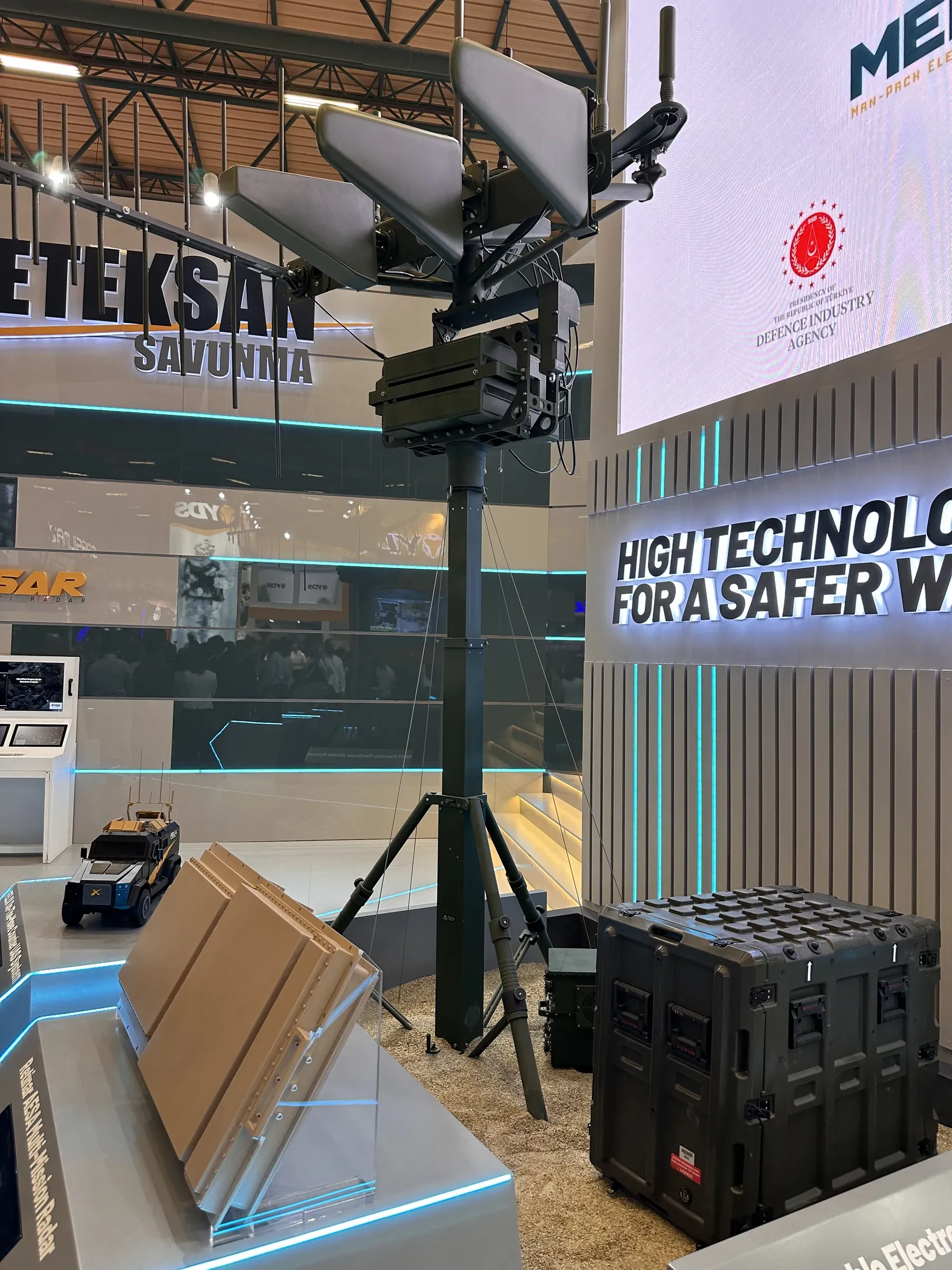 Mast on tripod holding antenna payload inside Meteksan indoor stand, ruggedised rack cases alongside.