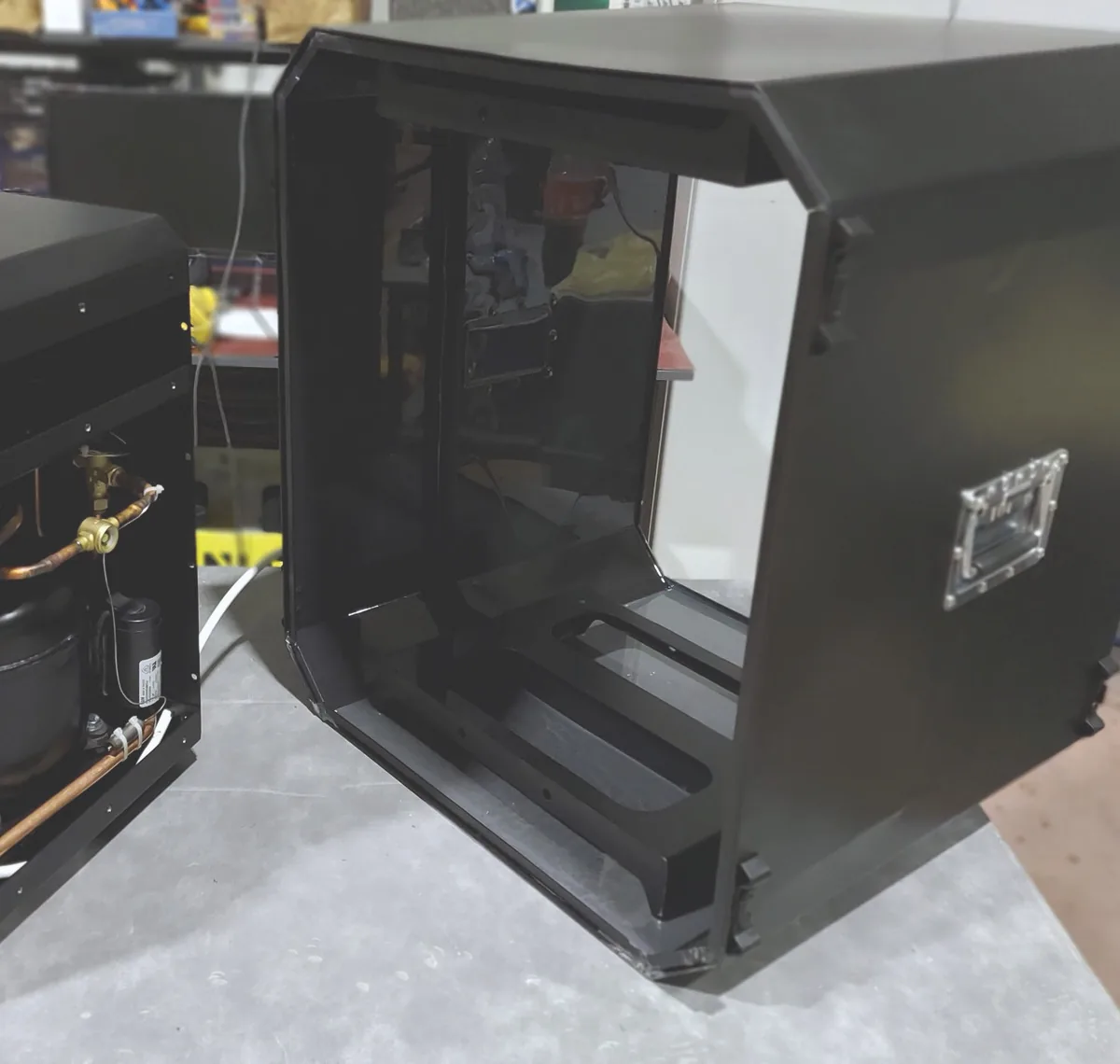 Half-assembled climate module on a workbench with a cabin shell beside it
