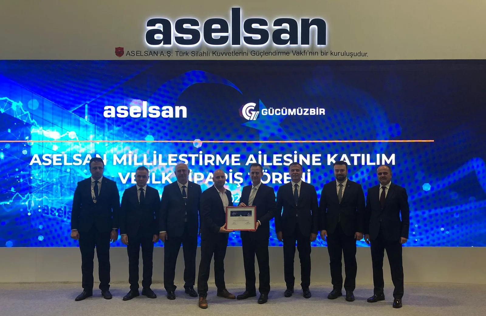 Eight people at the ASELSAN ceremony marking entry to its localisation programme and the first order, one of them holding the framed certificate.