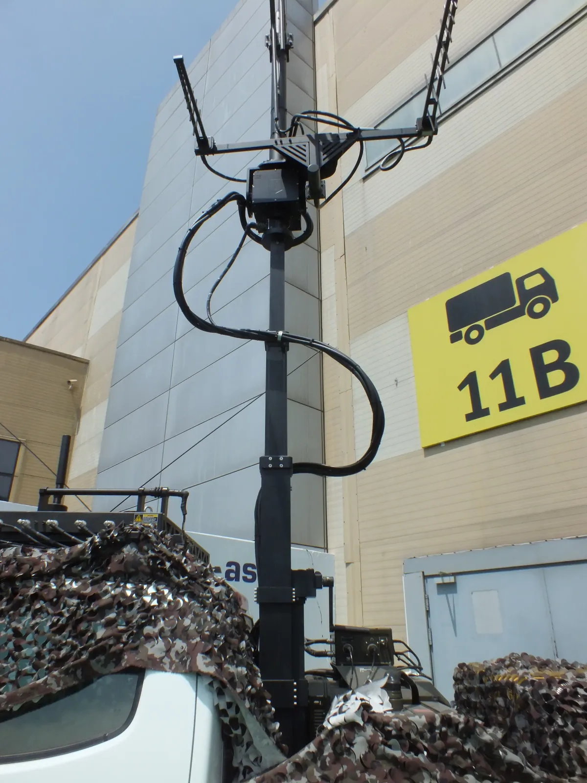 A manual telescopic mast extended on the stand, carrying its payload above the vehicle.