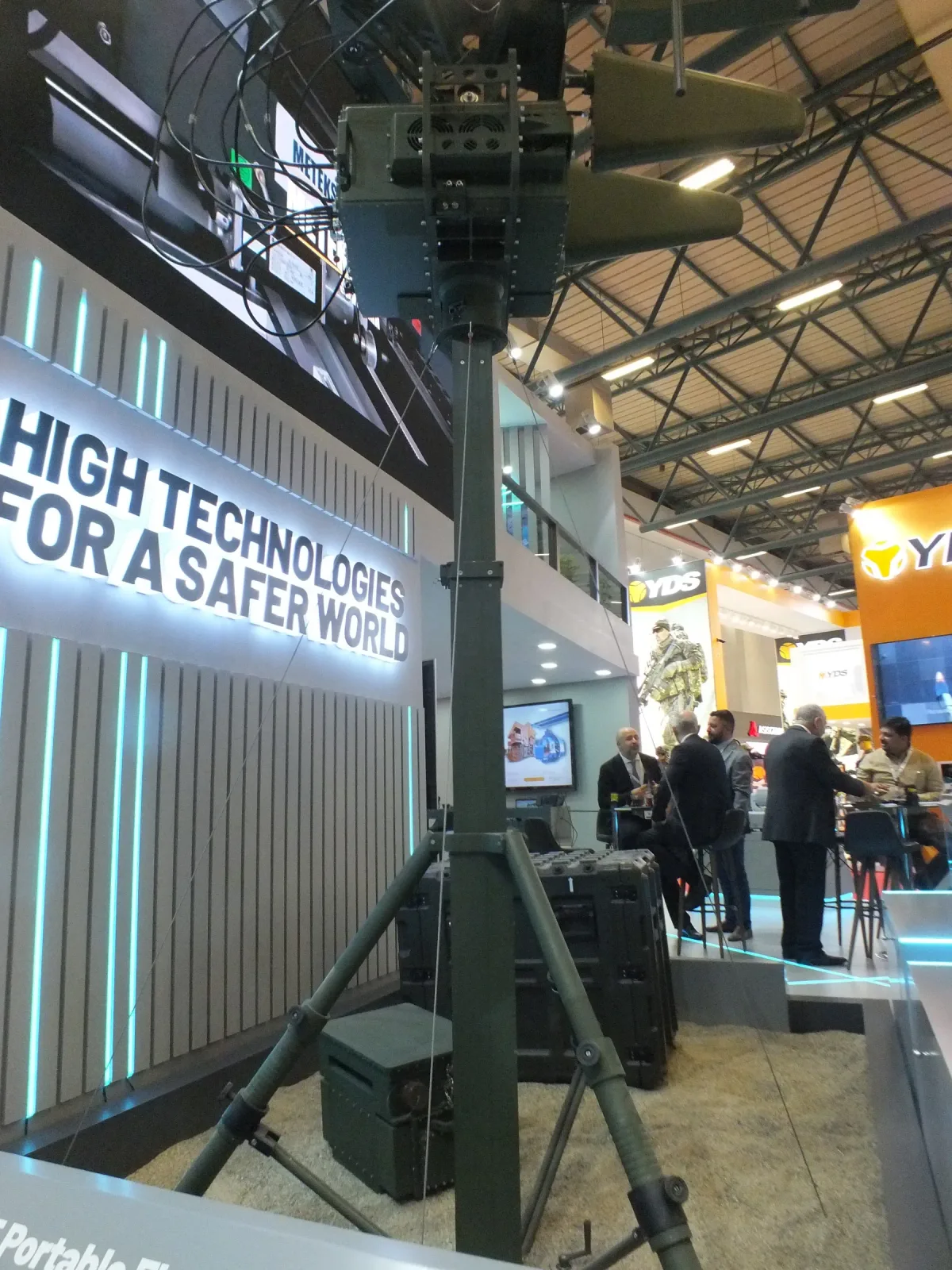 A manual telescopic mast on the stand carrying a directional antenna array at height.