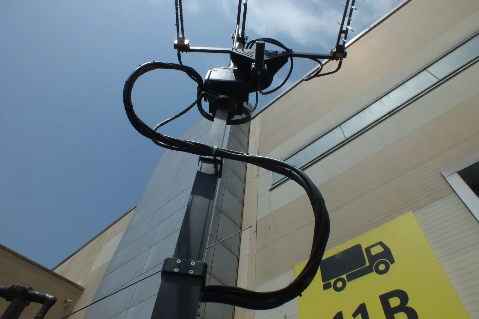 A manual telescopic mast on the stand carrying a directional antenna array at height.