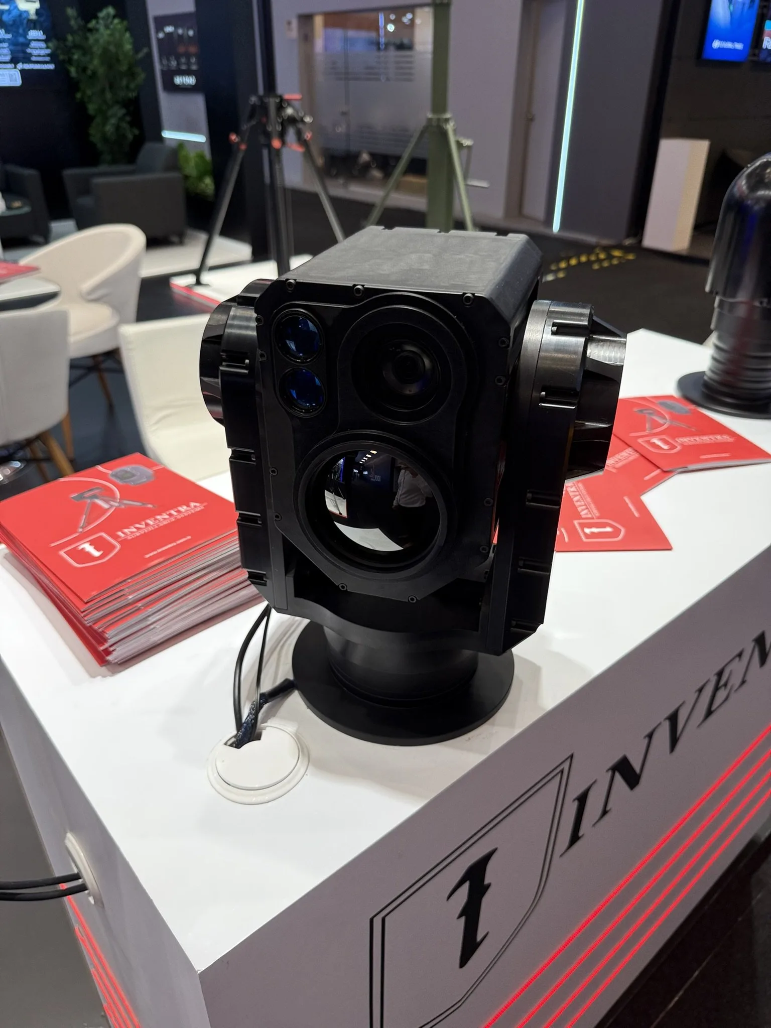 Box-type multi-aperture gimbal on the Inventra counter, brochures beside it.