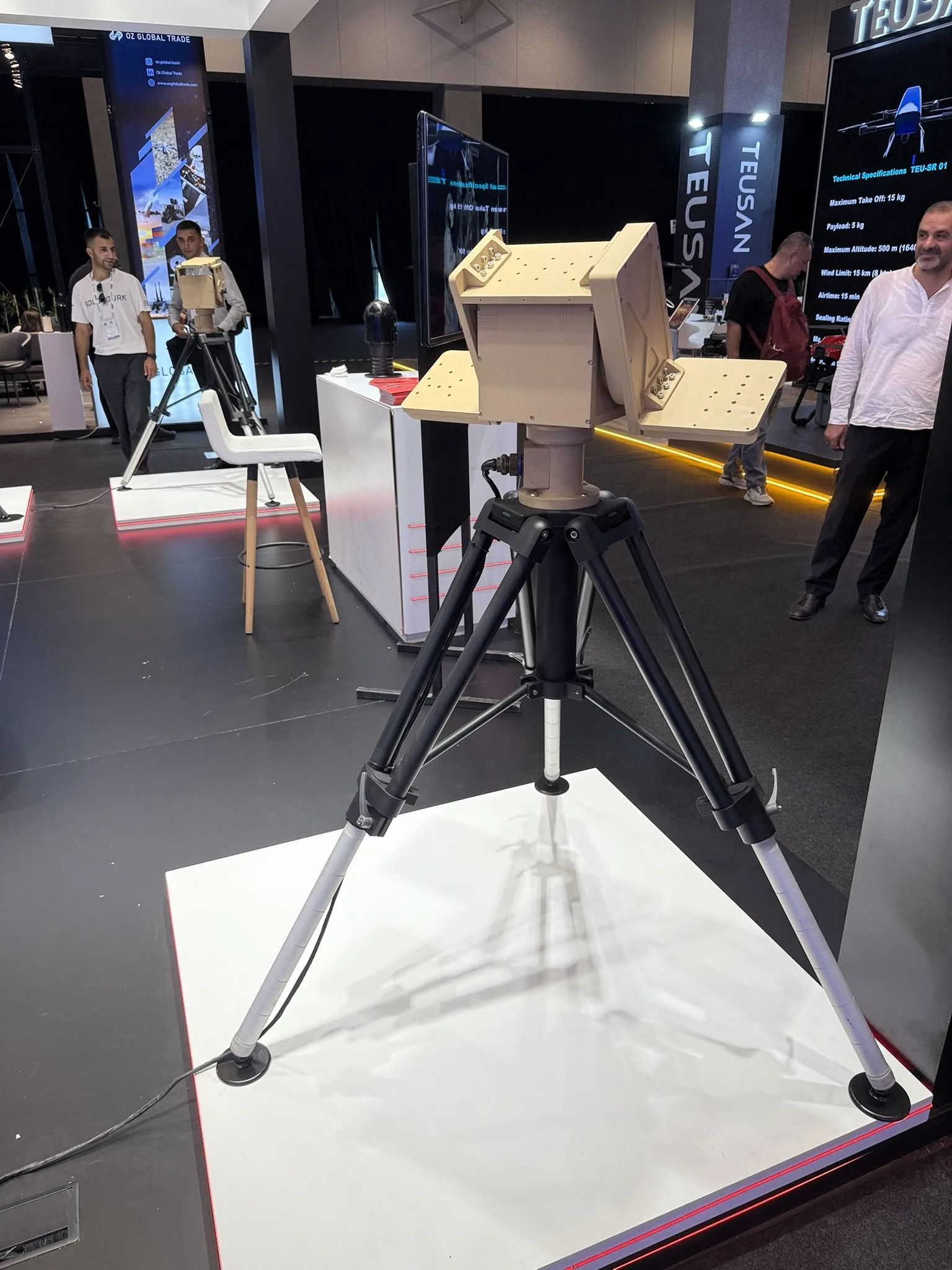 Sand-coloured pan-tilt unit with a mounting plate on each side, on a black tripod.