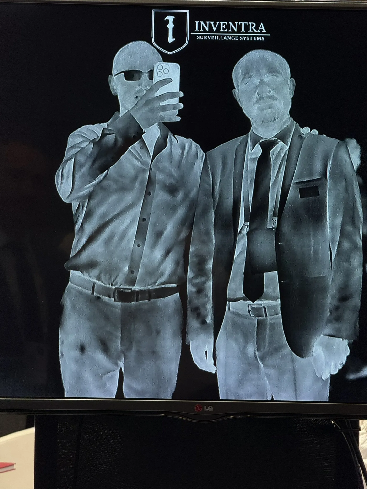 Screen on the stand showing a live thermal image of two people, the Inventra logo above the picture.