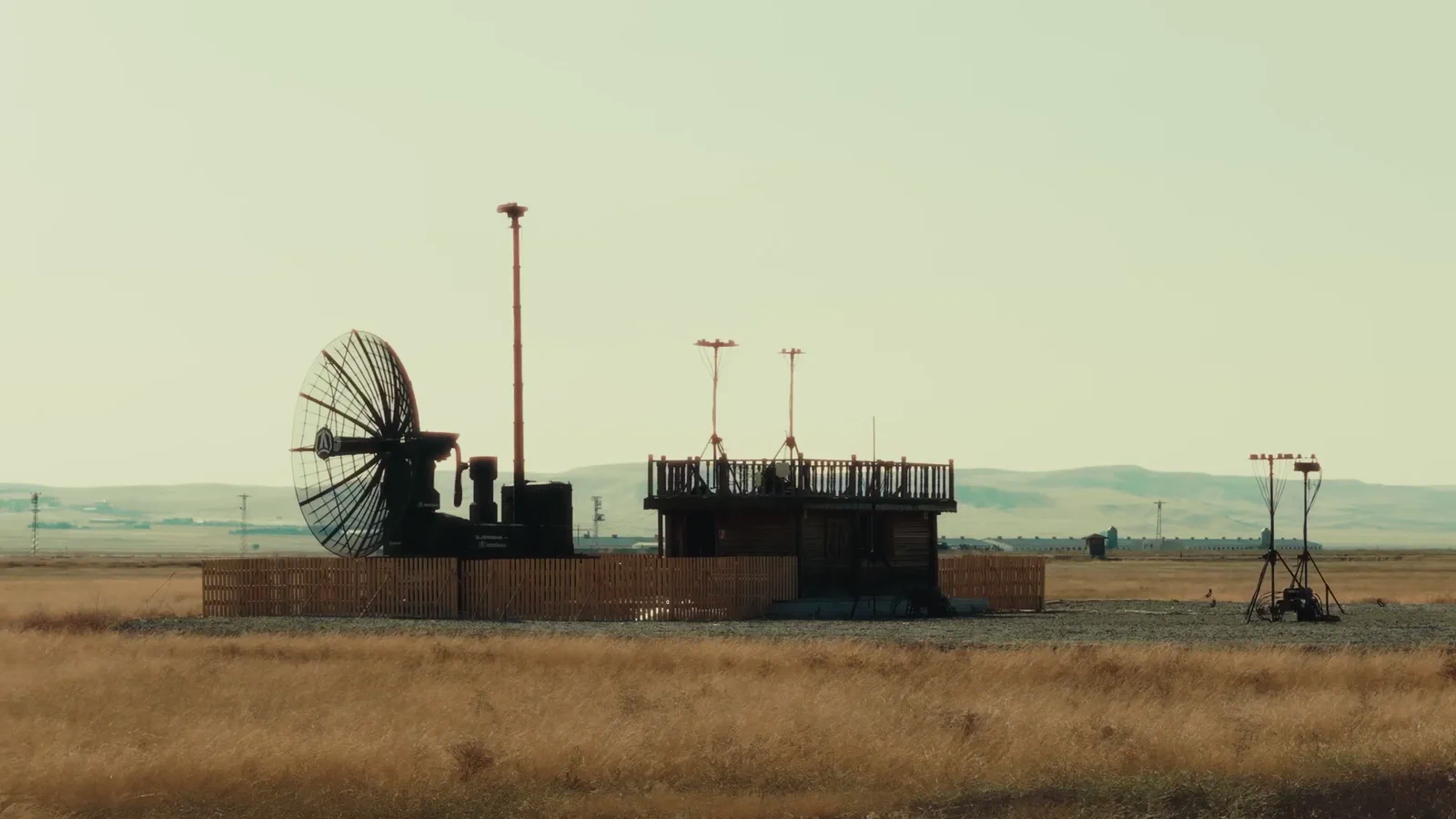 A counter-UAS site on open steppe: a mesh radar dish and a low platform, with guyed masts standing to the right.