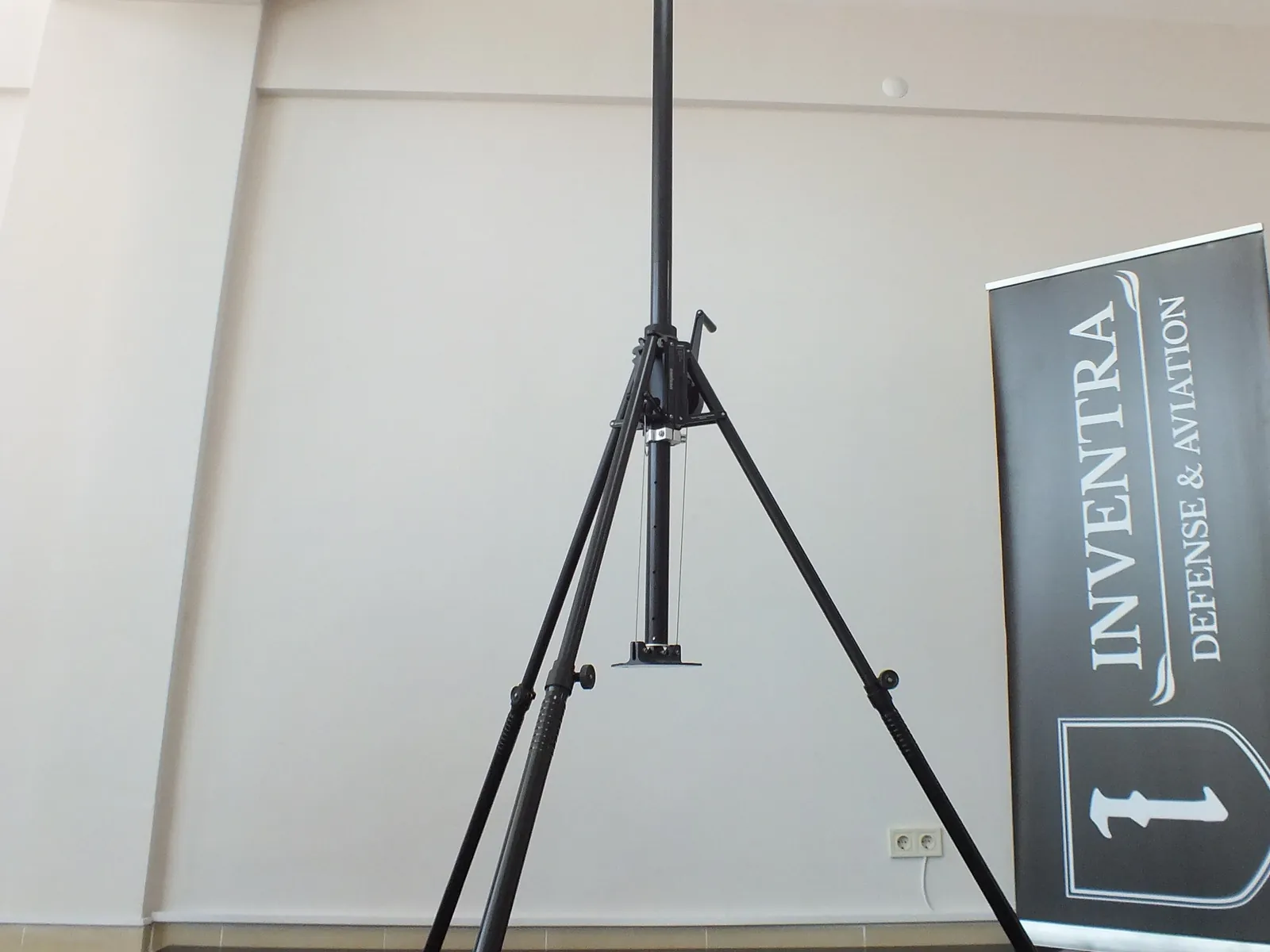 Complete ultra portable system — tripod with the mast retracted — in a plain empty room