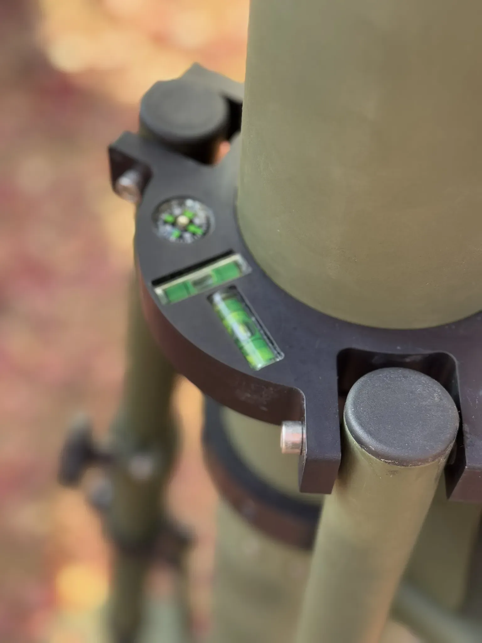 Close-up of the olive levelling collar with bubble level and compass clamped around the mast tube.