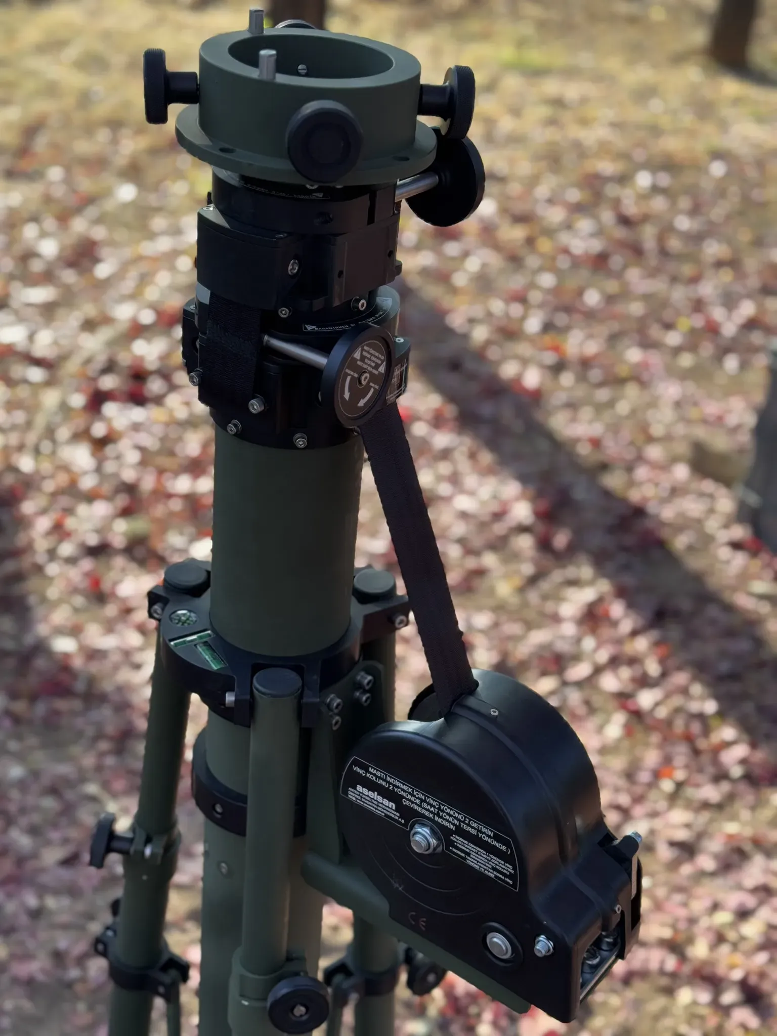 Upper mast head with rotator knobs and black winch assembly, standing on gravel outdoors.
