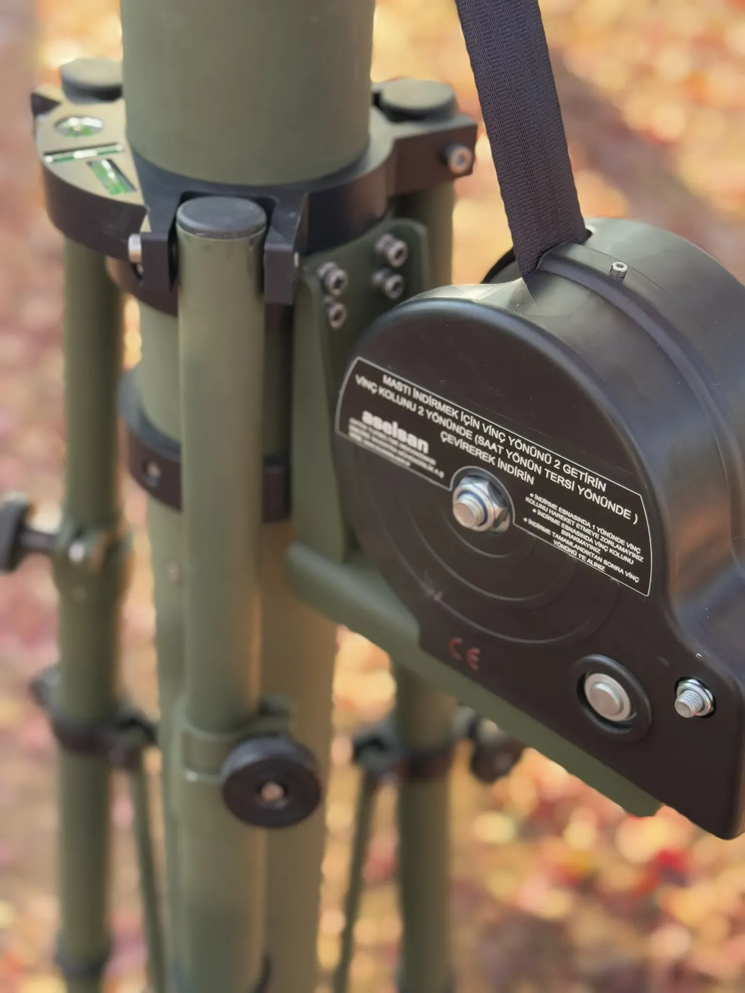 Winch housing and lifting strap on the olive mast between tripod legs, ASELSAN label readable.