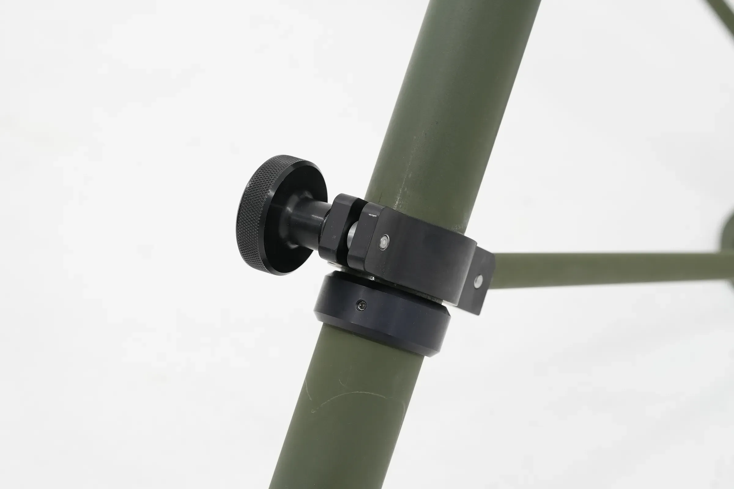Detail of black hinge collar joining a diagonal leg strut to the olive green mast tube.