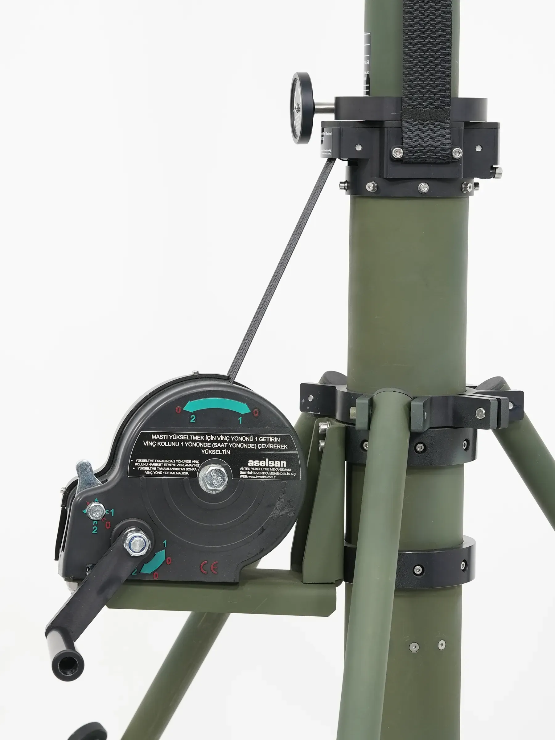 Winch, cable run and clamp brackets along the olive green mast tube seen from a low angle.