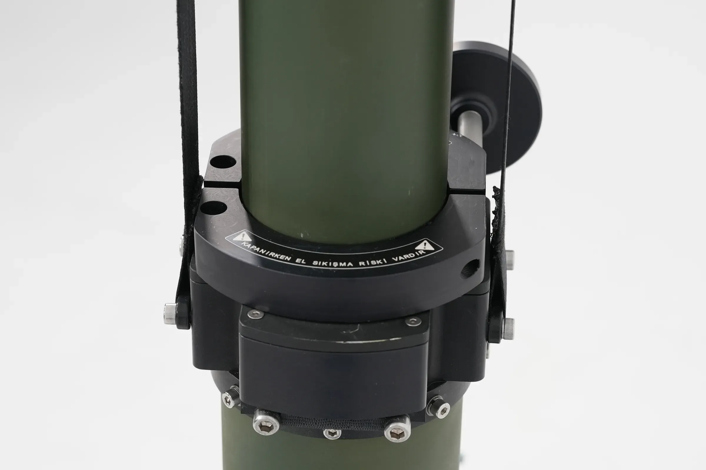 Black upper drive housing and cable brackets bolted around the top of the olive green mast tube.