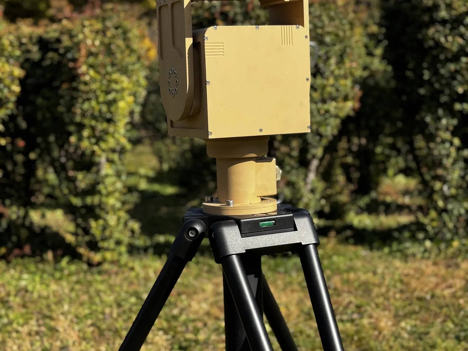Sun shade raised, on a tripod on garden ground, showing that the shade moves