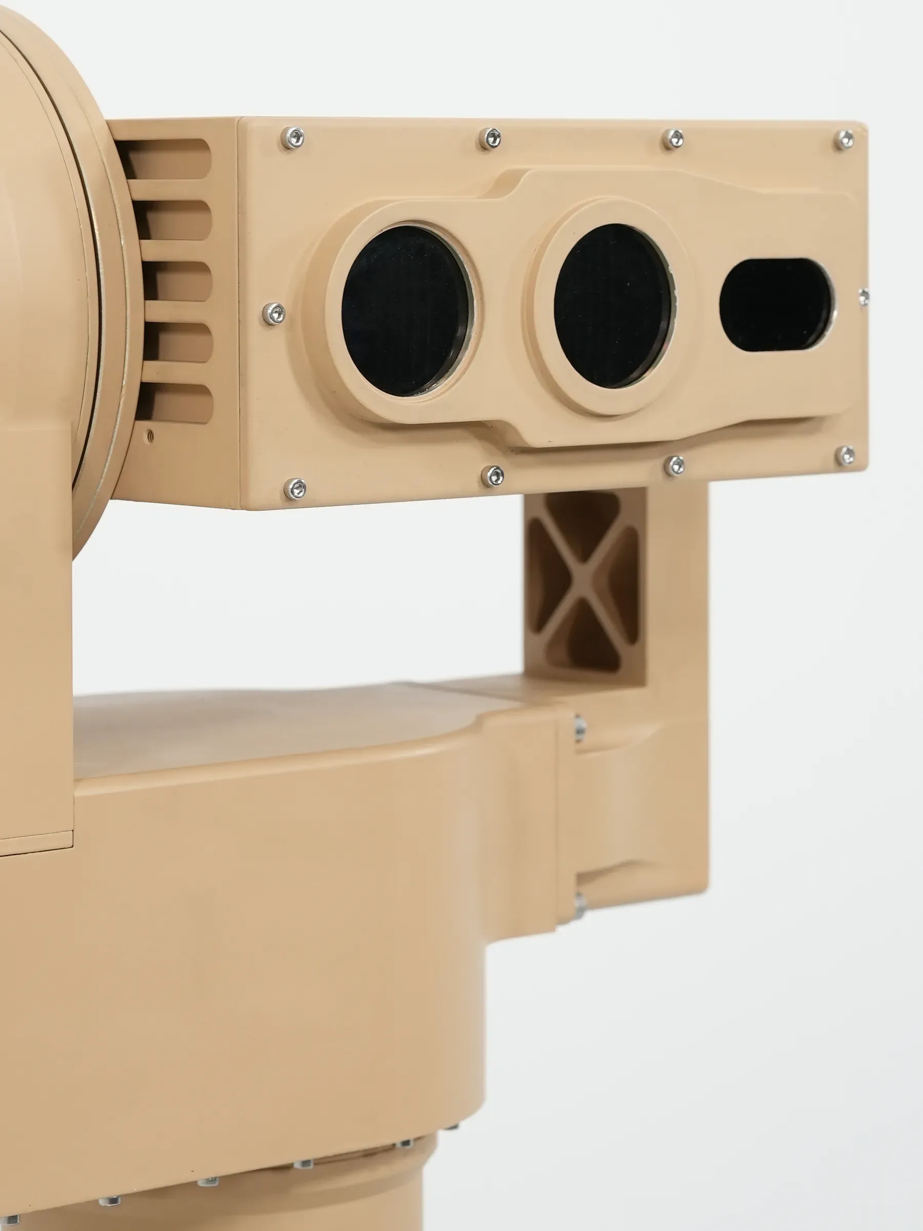 Close-up of the tan PED12 optics head showing its three front apertures and yoke arm.