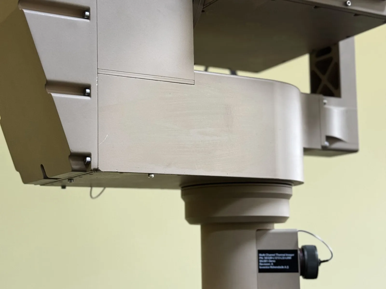 Front-right view from below, showing the optical window group and the mechanical structure of the yoke arm