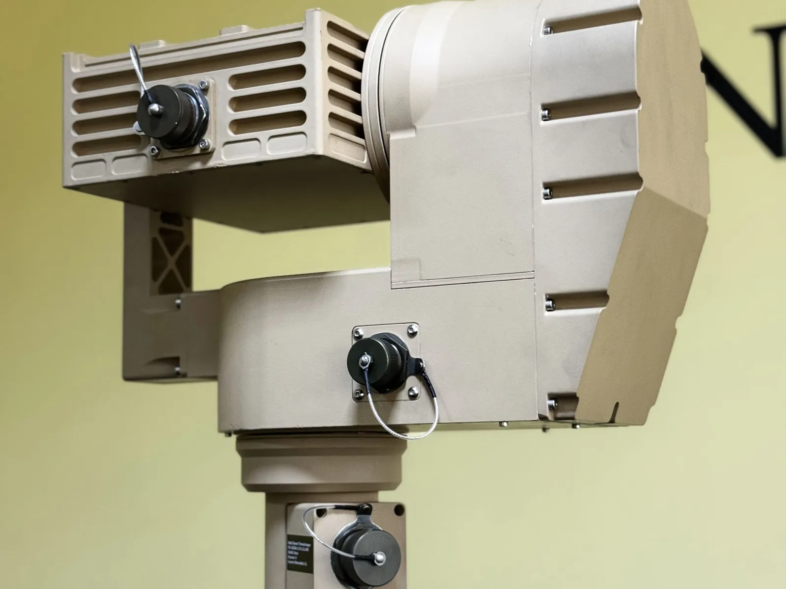 Rear-left three-quarter: the finned cooling surface of the thermal body, the tilt axis drum and the base