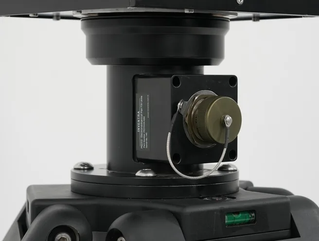 Studio detail of the black positioner base plate and drive motor with connector, mounted on the tripod head.