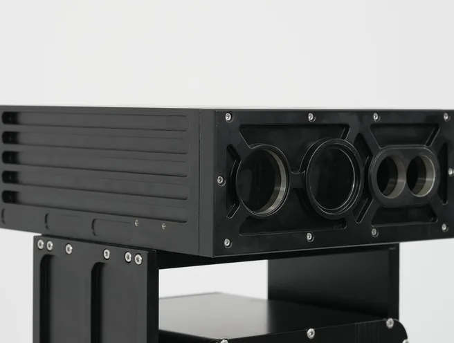 Studio close-up of the black SEB20 module showing its ribbed side and three recessed front apertures.