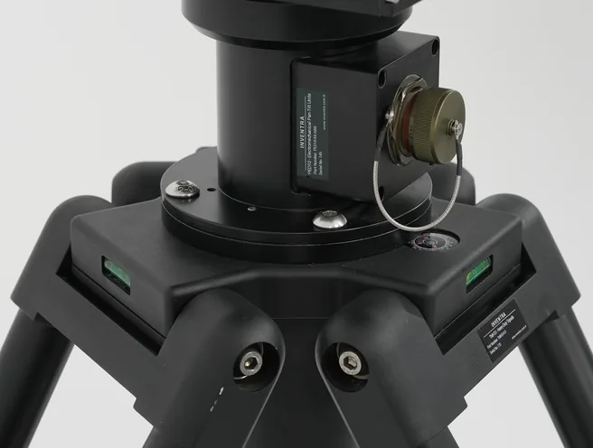 Studio detail of the black tripod head and positioner column with spirit levels and leg clamps.