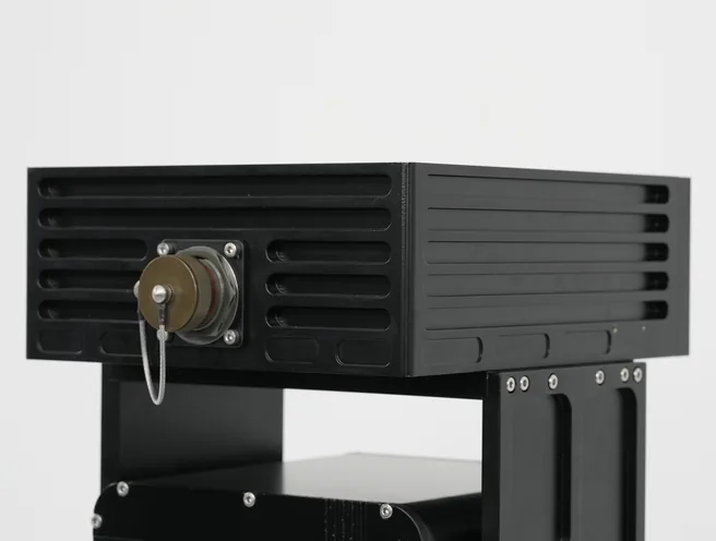 Studio close-up of the black SEB20 finned housing side face with tethered connector cap on the pivot.