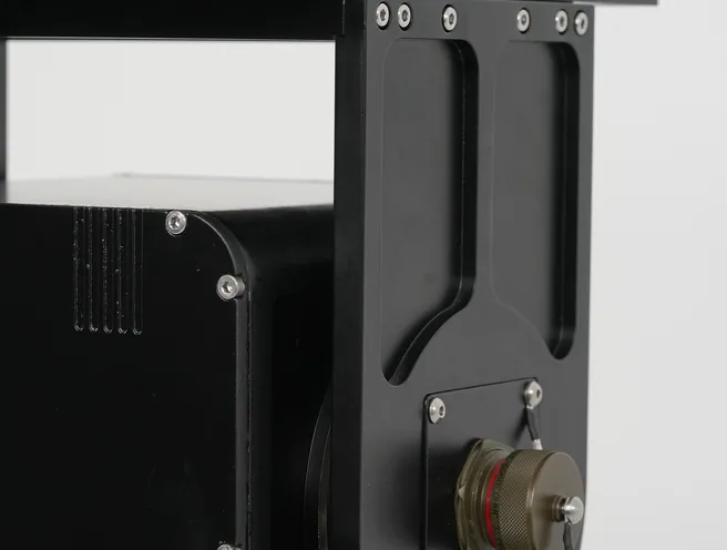 Tight studio detail of the black SEB20 module and yoke arm with brass elevation shaft connector.