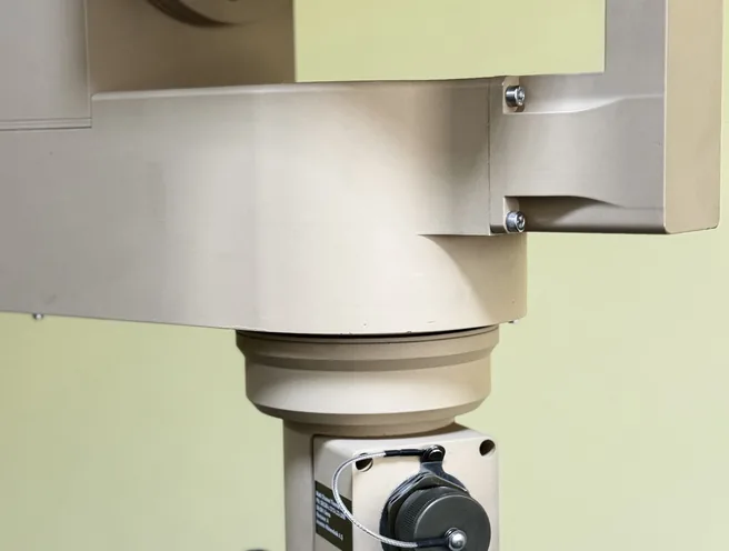 Indoor close-up of the PED12 azimuth column and drive motor beneath the tilted SEB20 payload, tripod head below.
