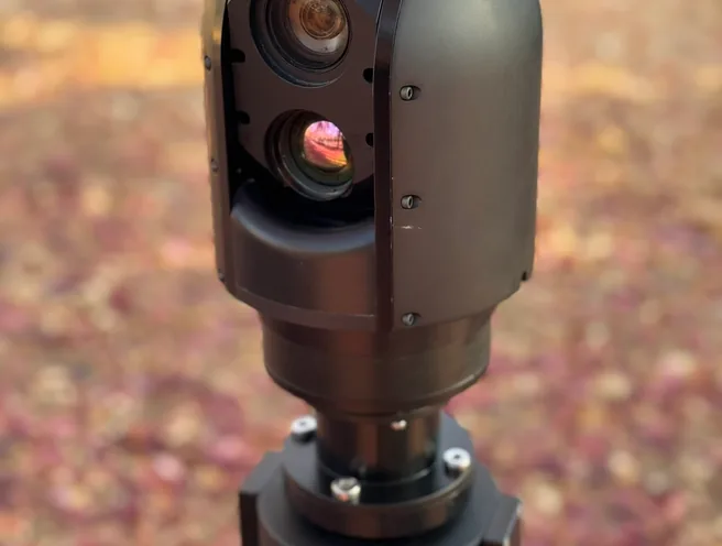 Tight outdoor close-up of the SEG10 gimbal head showing both lens apertures on the mast top.