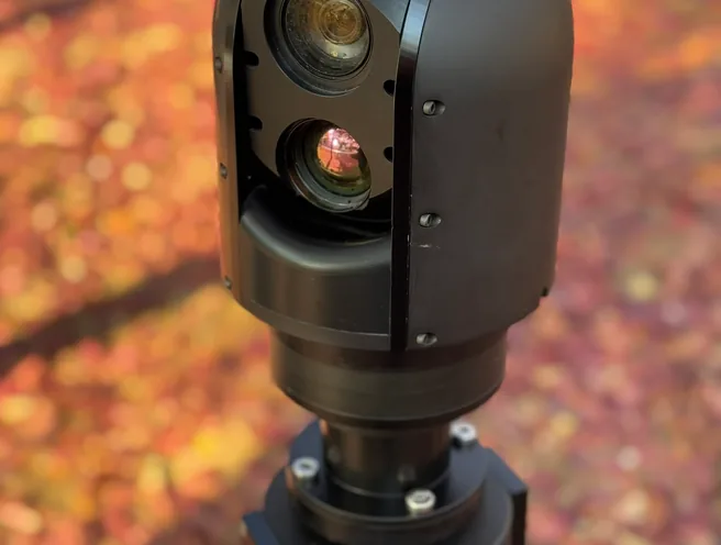 Close front view of the SEG10 gimbal head, day and thermal lenses catching low sun.