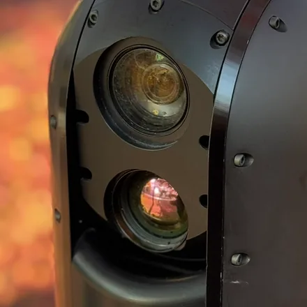 Close crop of the two stacked apertures on the front of the gimbal head, filling the square.