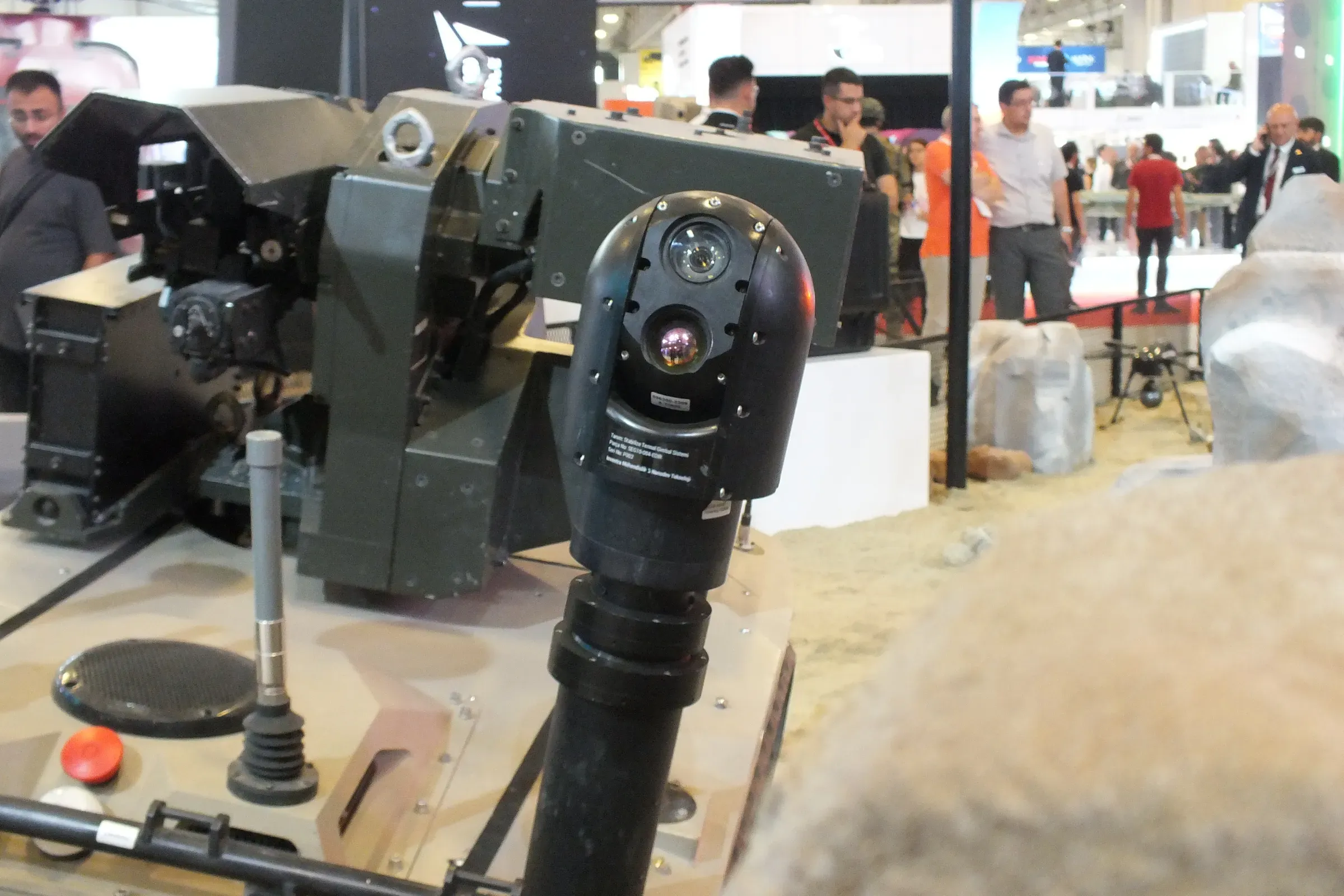 Close view of the SEG10 gimbal camera head mounted on the vehicle-mounted MES01 mast, exhibition crowd behind.