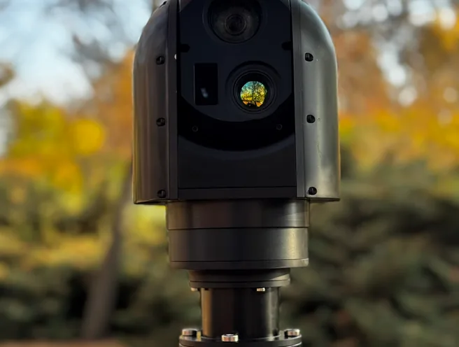 SEG12 gimbal head mounted on a positioner outdoors, lenses facing camera under bare trees.