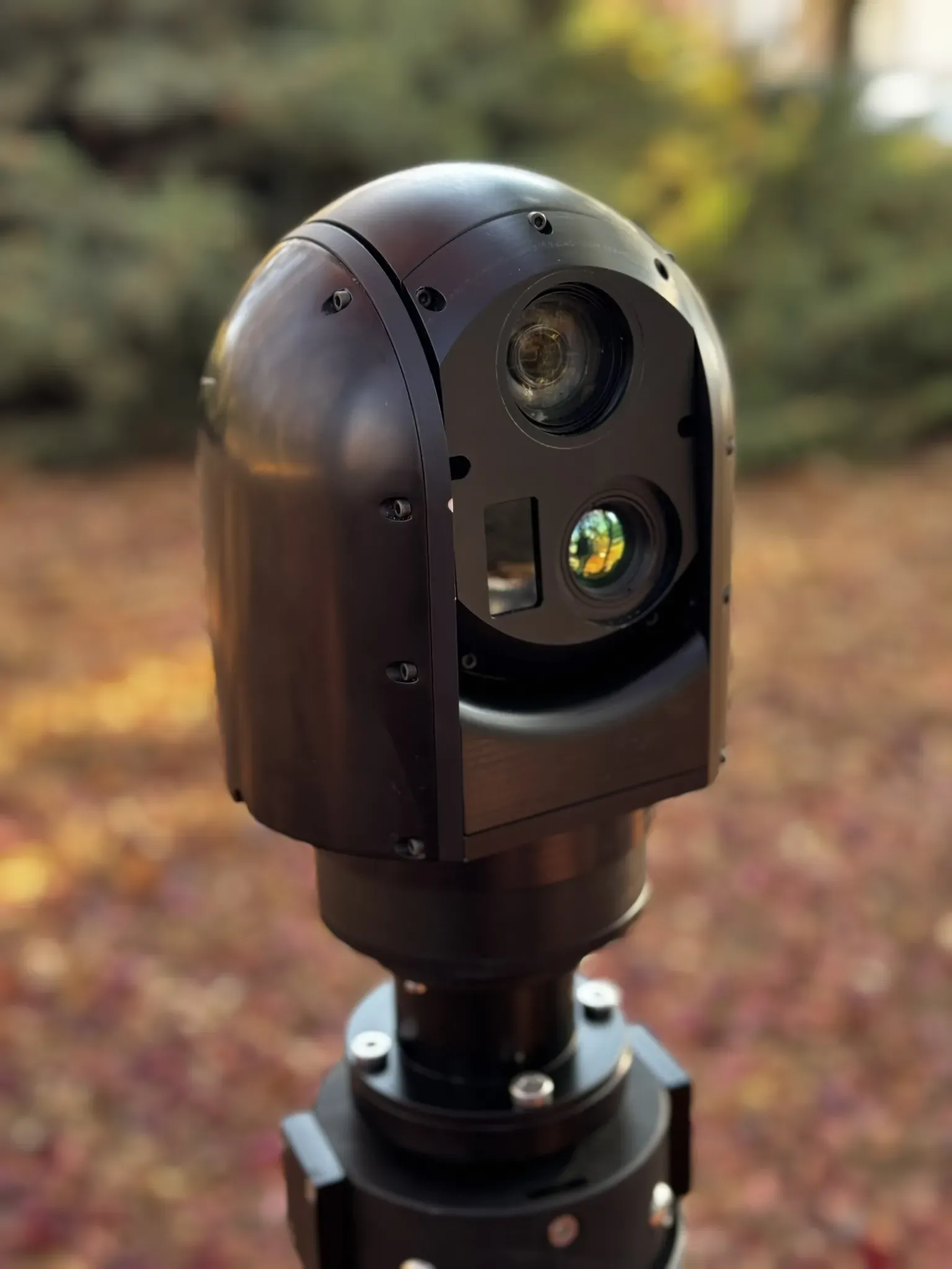 Close outdoor view of the SEG12 gimbal head with sunlit lens coatings above the mast joint.