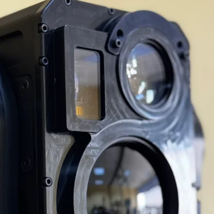 Close crop of the laser window among the lens barrels, angled so the window is distinct from the optics either side of it.