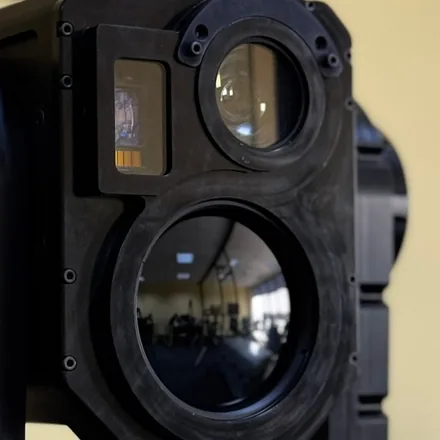 Close crop of the thermal barrel head-on beside the large day objective, so the two apertures can be compared.