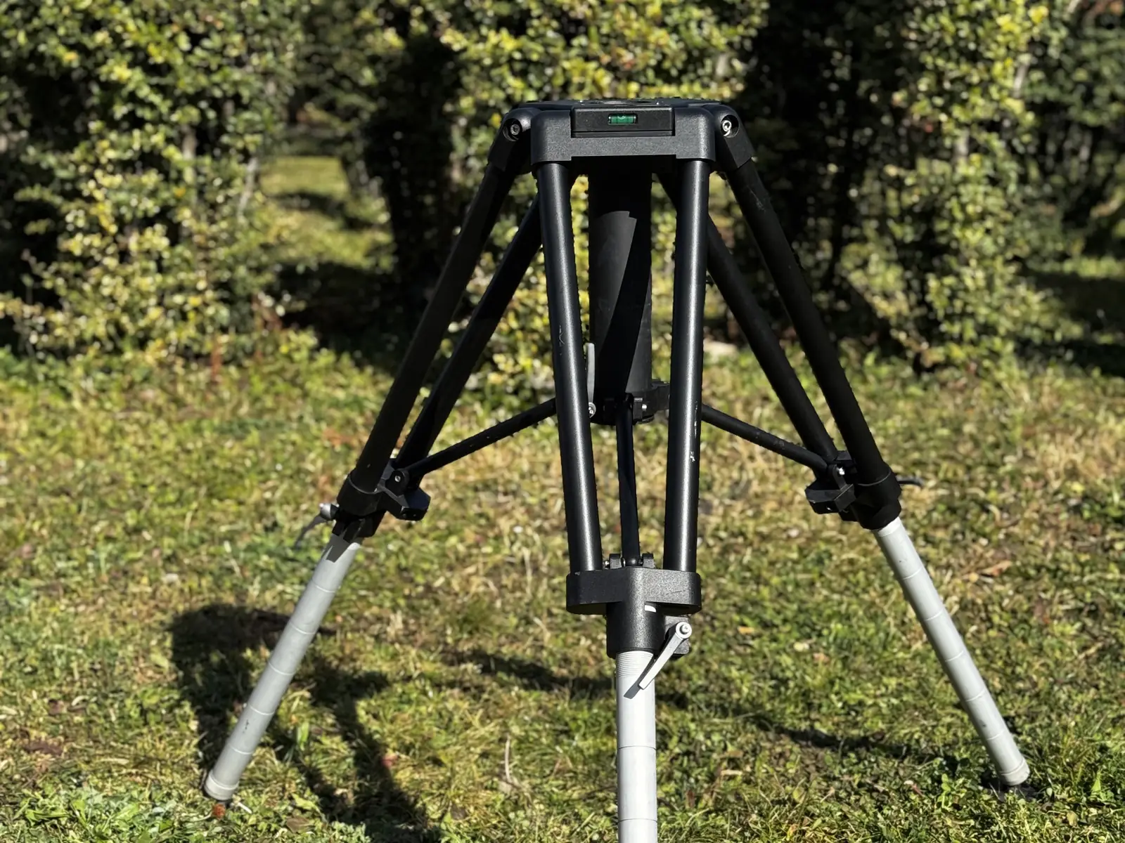 Heavy duty tripod fully spread on grass: hexagonal top plate, brace frame, three legs and pad feet