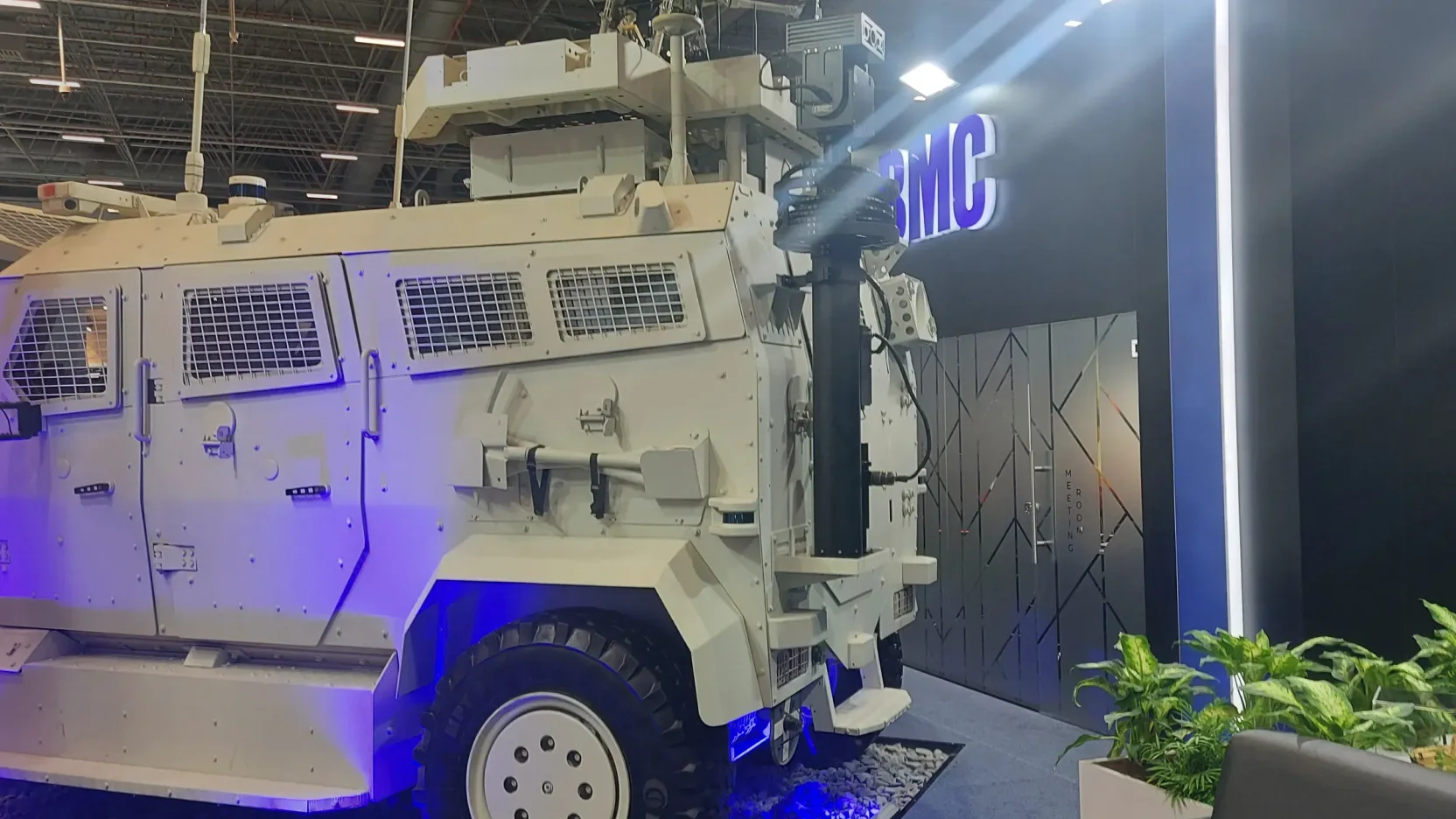 An armoured wheeled vehicle on an exhibition stand with a sensor head mounted above the crew compartment.